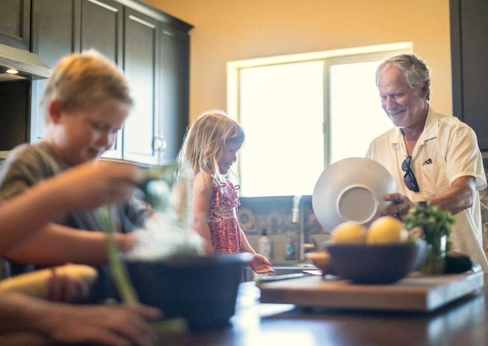 Three generations cooking together in a sunlit kitchen